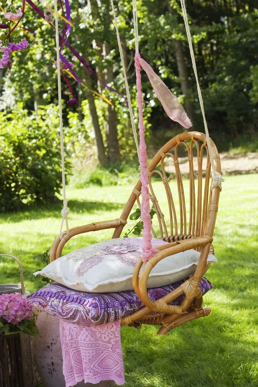 Подвесные качели из плетеного стула, украшенные яркими лентами
